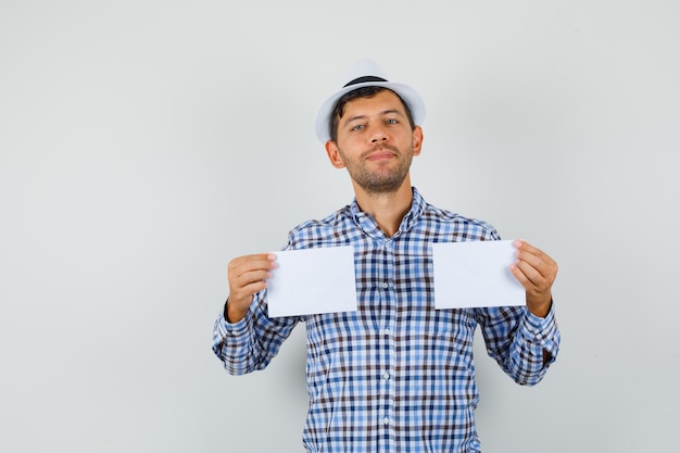 Young man holding paper sheets in checked shirt