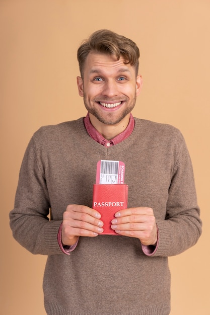 Бесплатное фото Молодой человек держит паспорт и билеты на самолет для путешествия