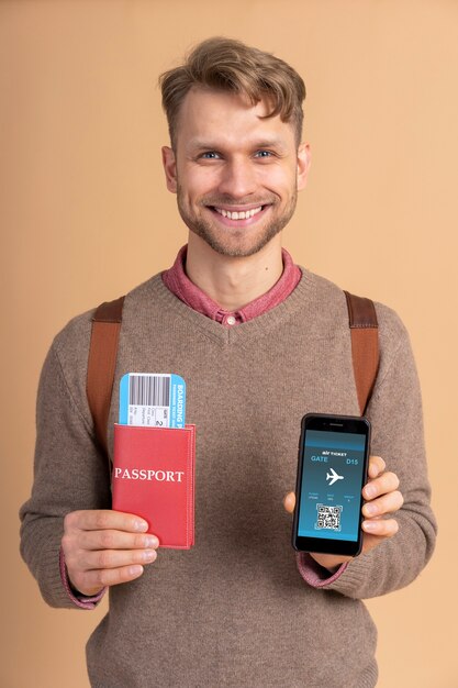 Young man holding passport with plane tickets and smartphone