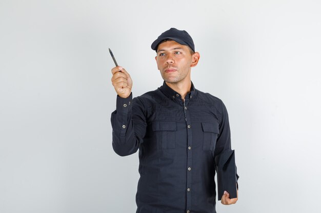 Young man holding pen and folder in black shirt with cap