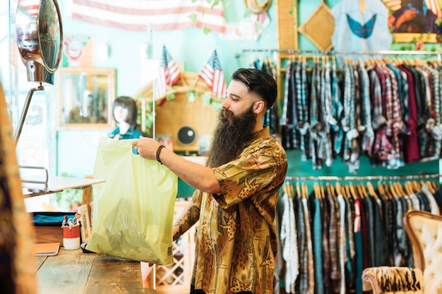 Young man holding plastic bag in boutique