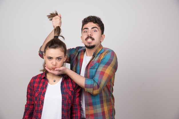 Young man holding a ponytail of woman and posing.