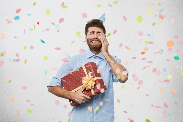 Young man holding present surrounded by confetti