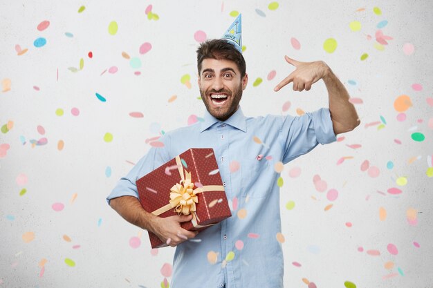 Young man holding present surrounded by confetti