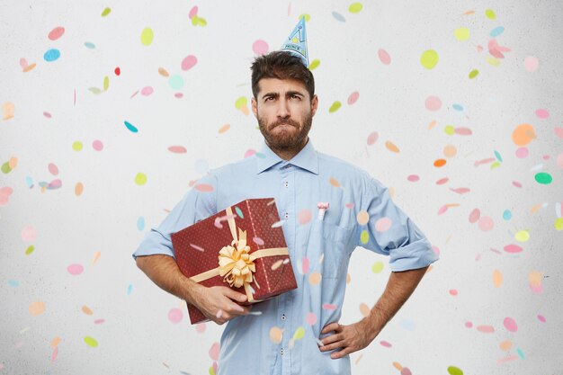 Young man holding present surrounded by confetti