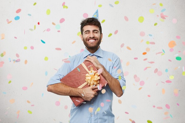 Young man holding present surrounded by confetti