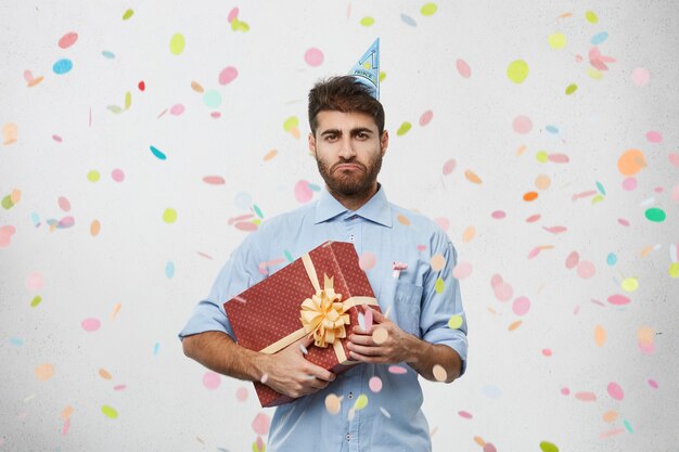 Young man holding present surrounded by confetti