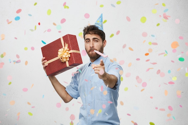 Free photo young man holding present surrounded by confetti