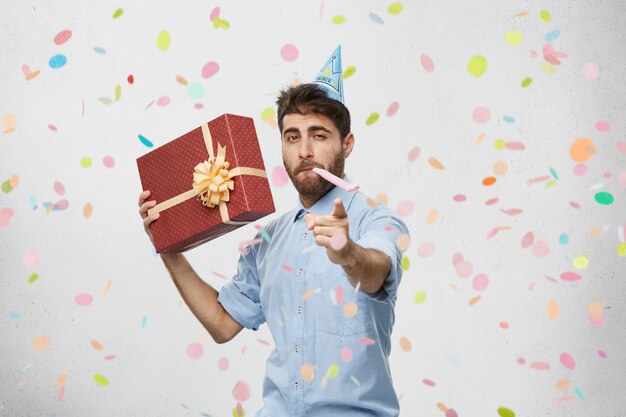 Young man holding present surrounded by confetti