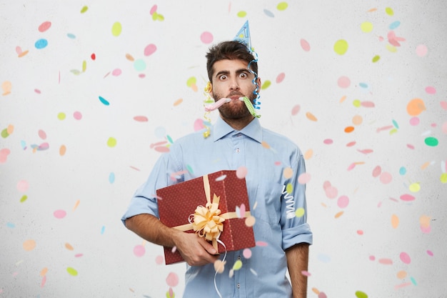 Free photo young man holding present surrounded by confetti