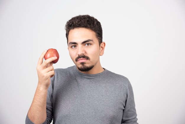 Young man holding red apple angrily.