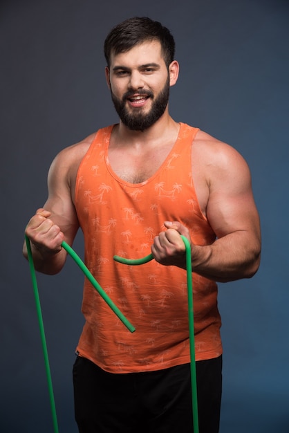 Young man holding rubber for sport on dark blue wall.