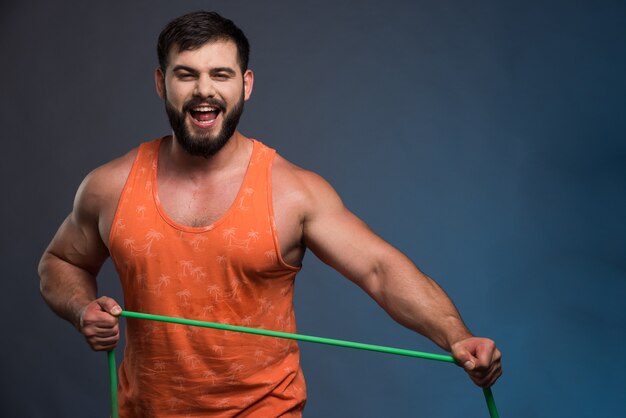 Young man holding rubber for sport on dark blue wall.