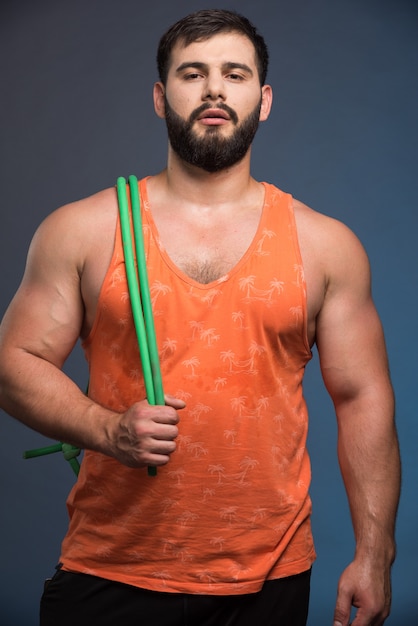 Free photo young man holding rubber for sport on dark blue wall.