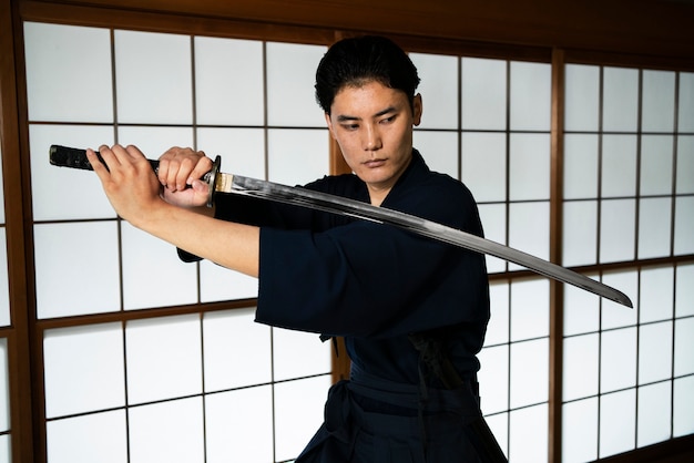 Young man holding samurai sword medium shot