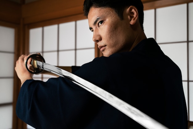 武士の刀の側面図を保持している若い男