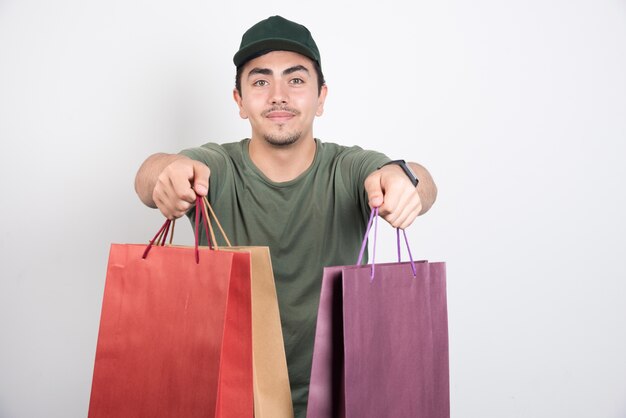 Young man holding shopping bags on white background.