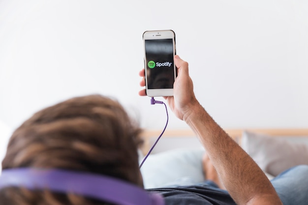 Young man holding smartphone with spotify app