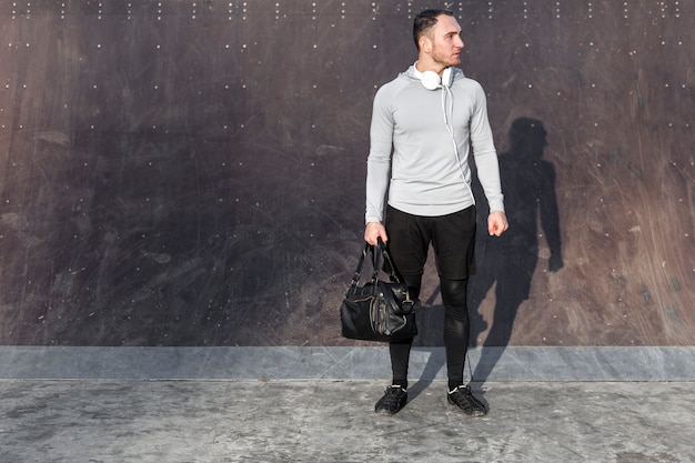 Young man holding a sport bag and looking away