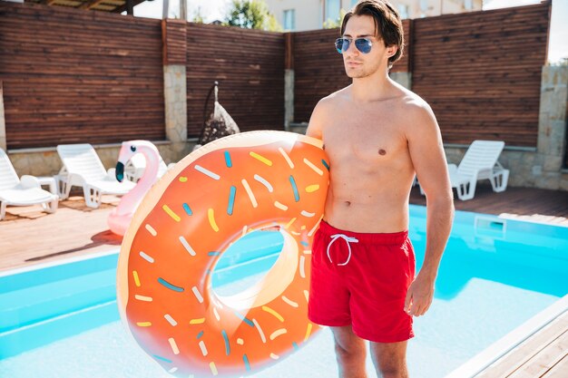 Young man holding a swim ring