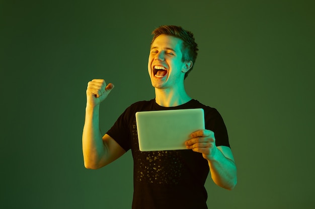 Free photo young man holding tablet, celebrating