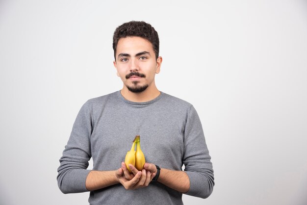 A young man holding two fresh bananas .