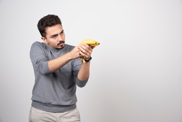 A young man holding two fresh bananas .