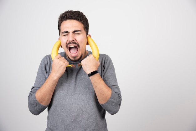 A young man holding two fresh bananas .