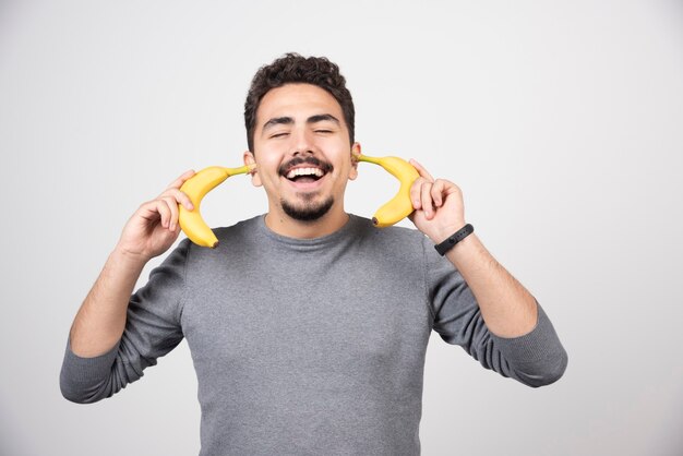 두 개의 신선한 바나나를 들고 젊은 남자.