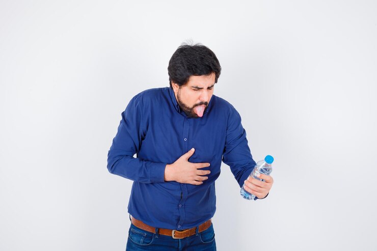 मुफ़्त फोटो young man holding water bottle and having bellyache in blue shirt and jeans and looking harried. front view.