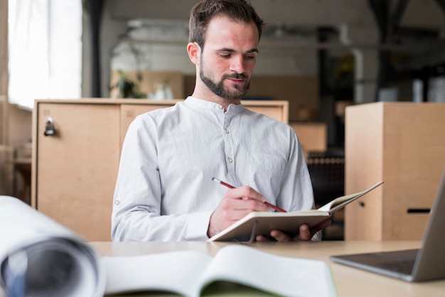 Free photo young man holding writing on diary in office