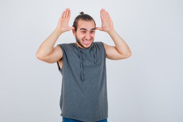 Young man in hoodie making grimace and looking cheerful , front view.