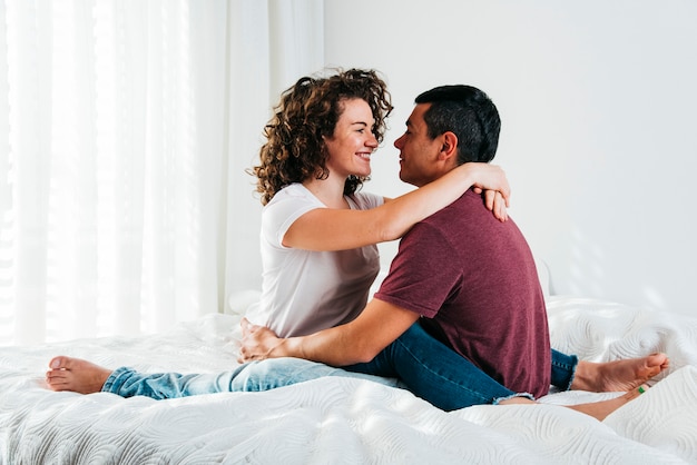 Young man hugging happy woman on bed