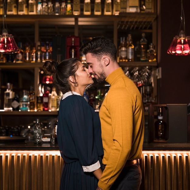 Free photo young man hugging with charming woman near bar counter