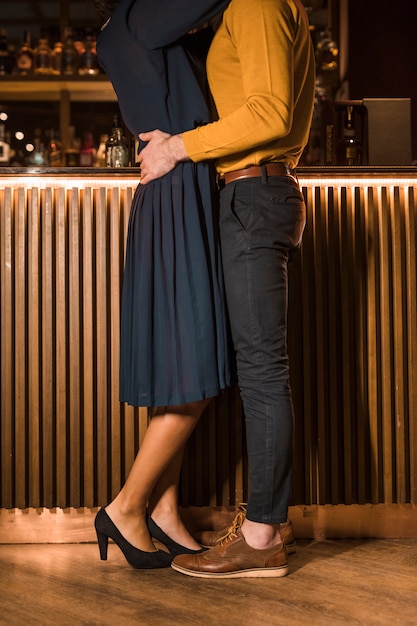 Young man hugging with slim woman near bar counter