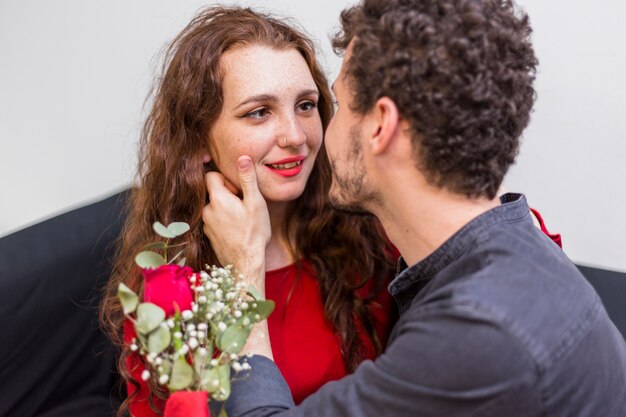 Young man hugging woman with red rose 