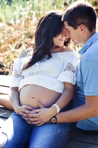 Young man hugs woman tender and touches her pregnant belly