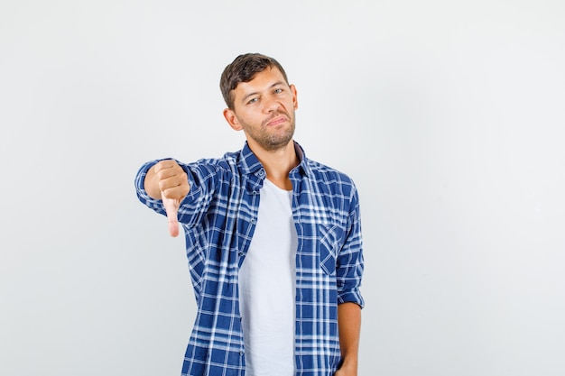 Молодой человек в рубашке показывает палец вниз и недоволен, вид спереди.