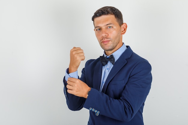 Young man inserting button on his wrist in suit and looking confident.