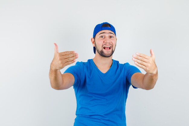 Young man inviting to come in blue t-shirt and cap 