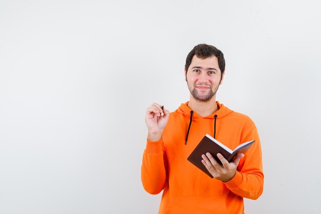 The young man is holding a book and a pen  on white background