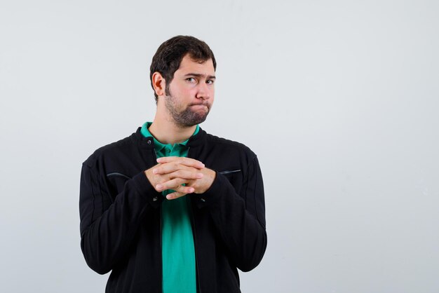 The young man is looking at camera by crossing fingers on white background