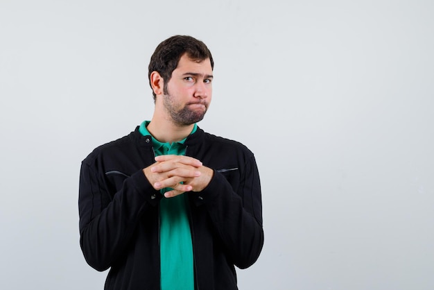 The young man is looking at camera by crossing fingers on white background