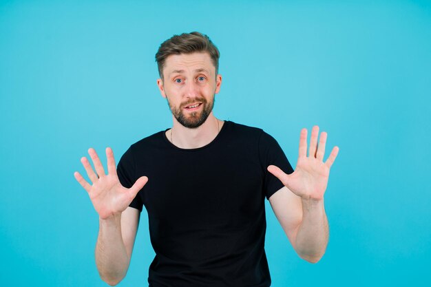 Young man is opening hands and showing handfuls on blue background