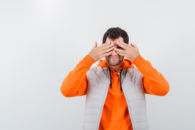 The young man is peeking through his fingers on white background