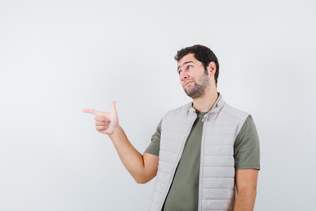 The young man is pointing to left with forefinger  on white background