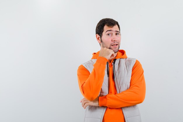 The young man is putting his hand on chin on white background