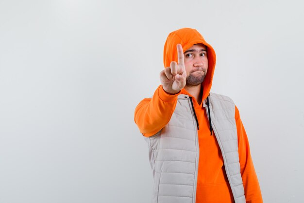 The young man is showing a minute gesture with forefinger on white background