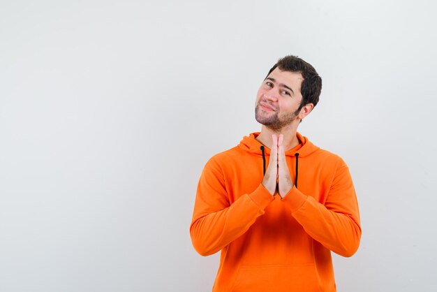 The young man is showing thanks gesture by connecting hands on chest on white background