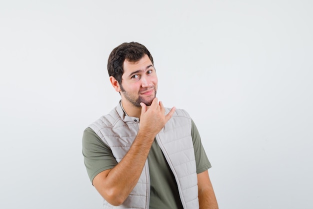 The young man is smiling by putting his hand on chin  with hand on white background